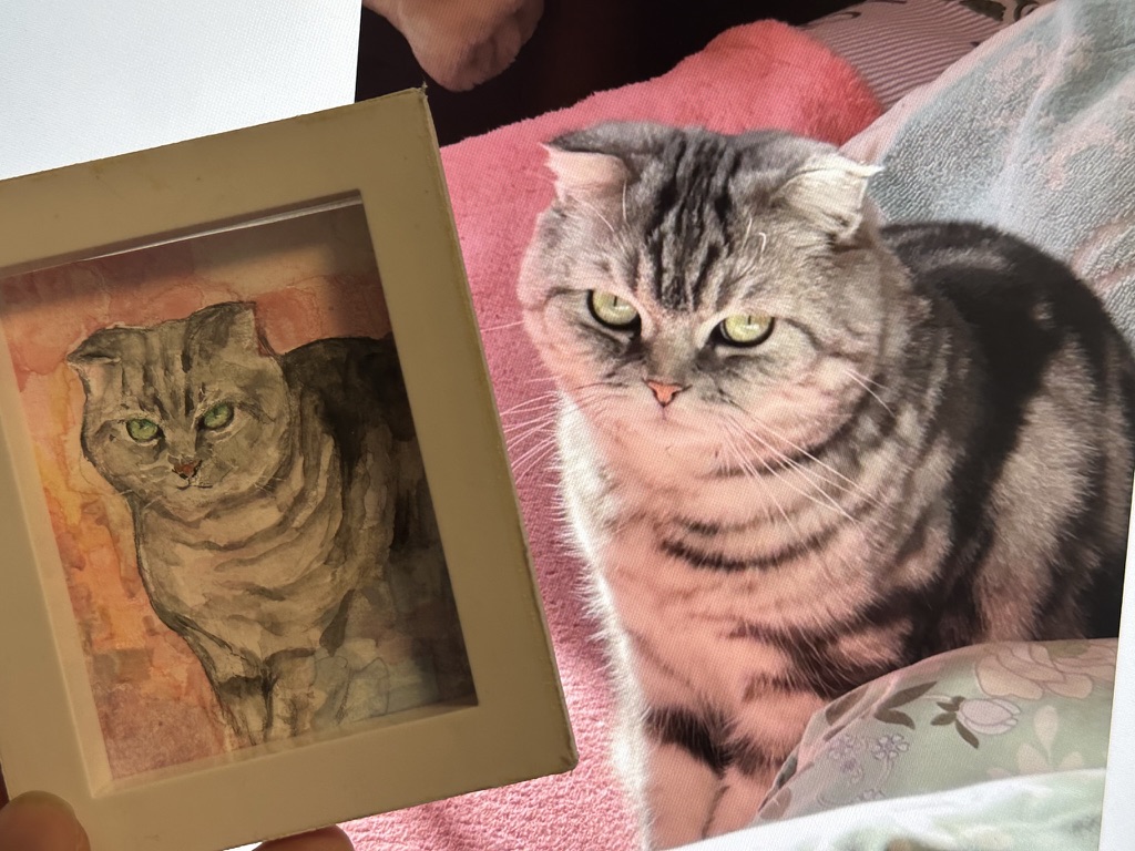 A cat beside a painted pet portrait